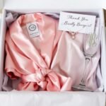 Personalized bridesmaid gift box with monogrammed items including a silk robe, champagne flute, and jewelry
